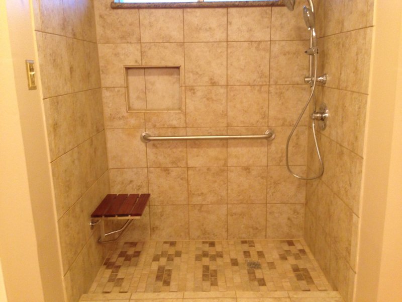 stone and tile ada compliant bathroom with shower seat and grab bars
