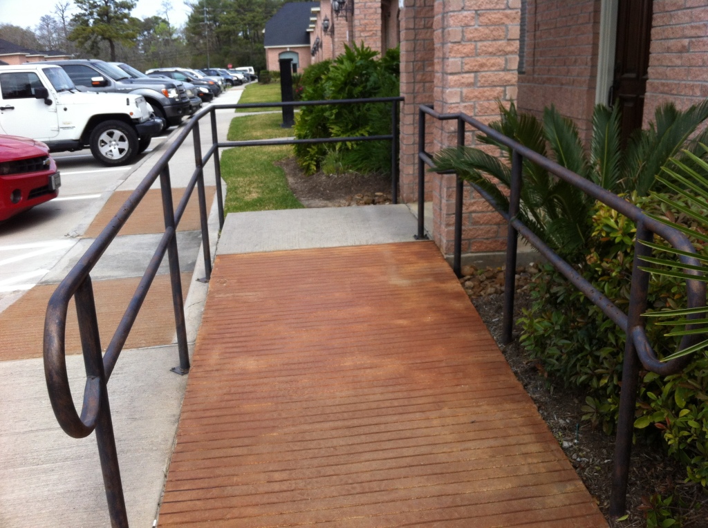 A concrete wheelchair ramp with rails in a light commercial zone.